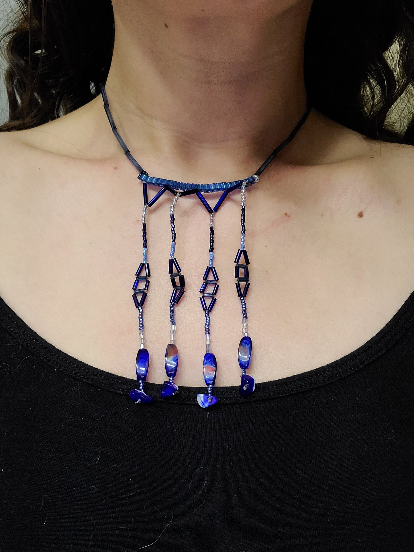 Model wearing blue tone chandelier fringe statement necklace