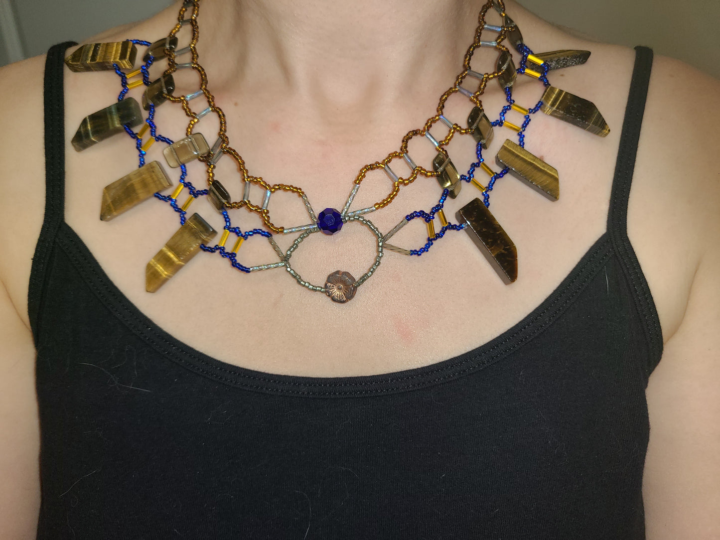 Woman wearing cobalt and amber toned tiger eye collar necklace.