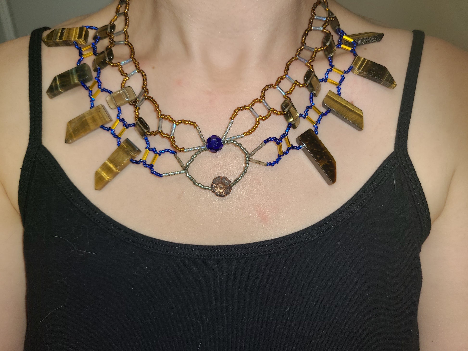 Woman wearing cobalt and amber toned tiger eye collar necklace.