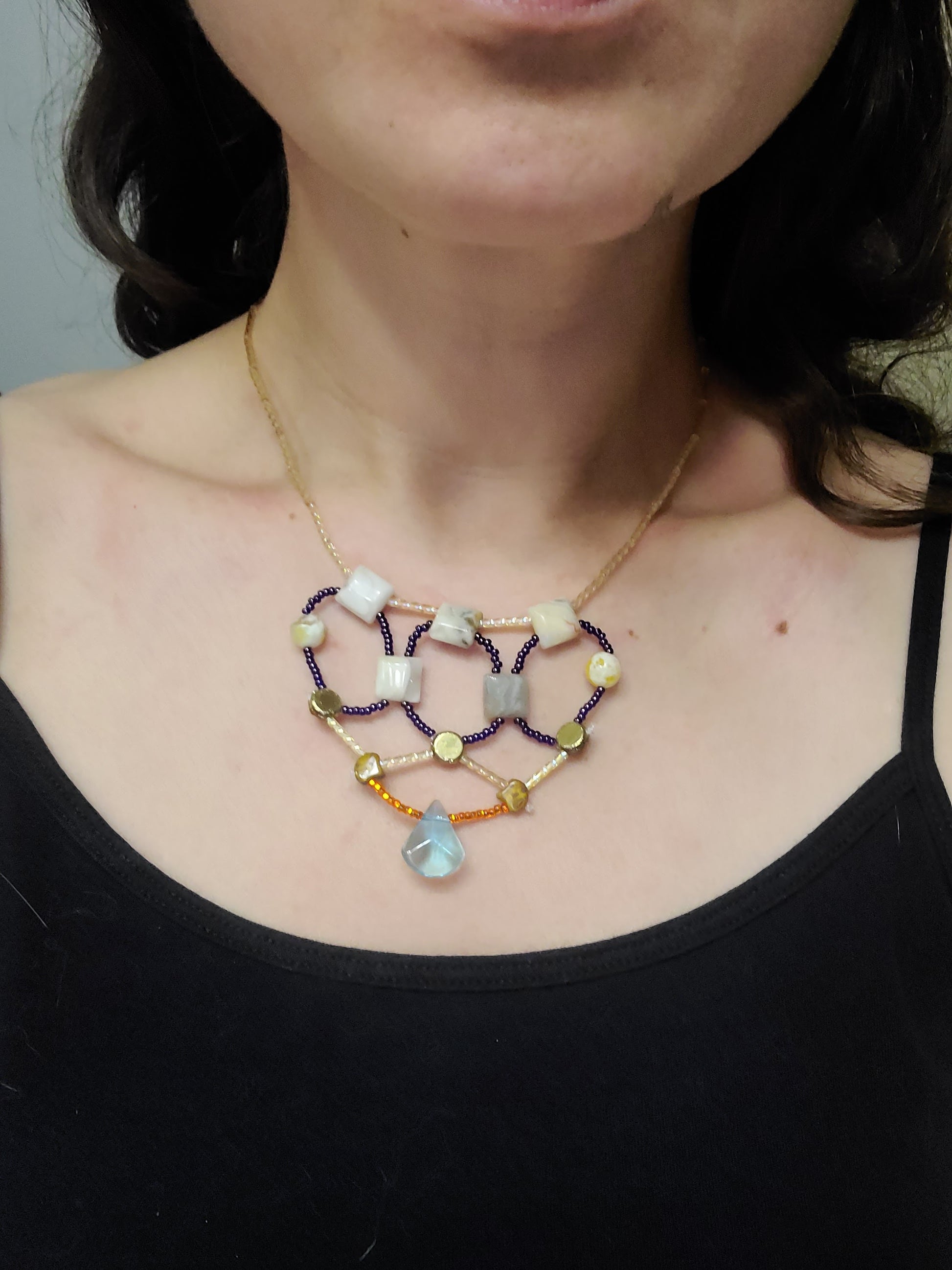 Woman wearing gold and cobalt toned crazy lace agate necklace.