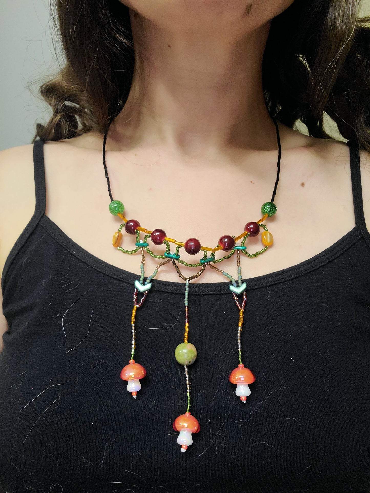 Woman wearing cottagecore statement necklace with mushrooms and unakite
