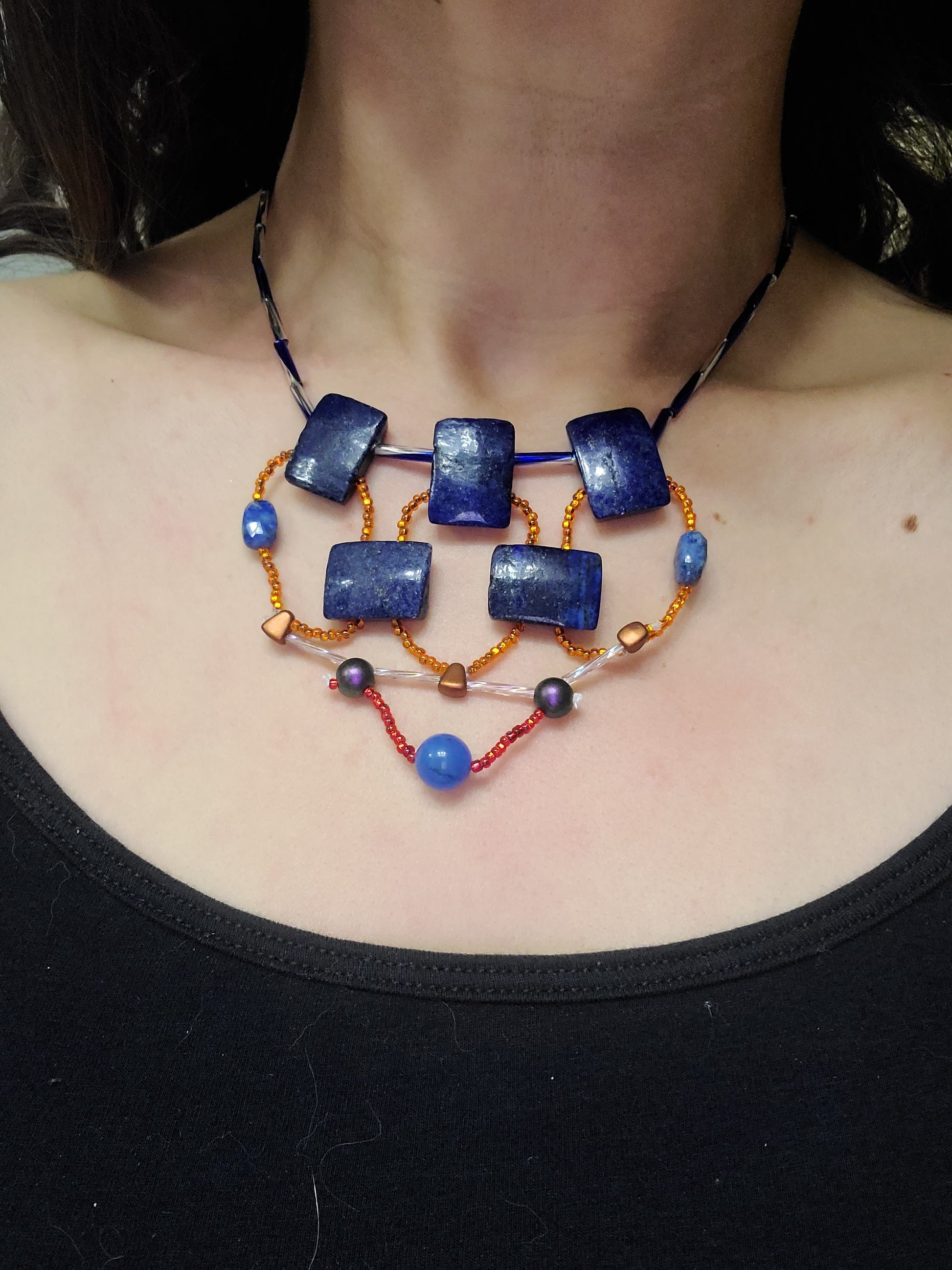 Dark-haired woman wearing lapis mosaic statement necklace.