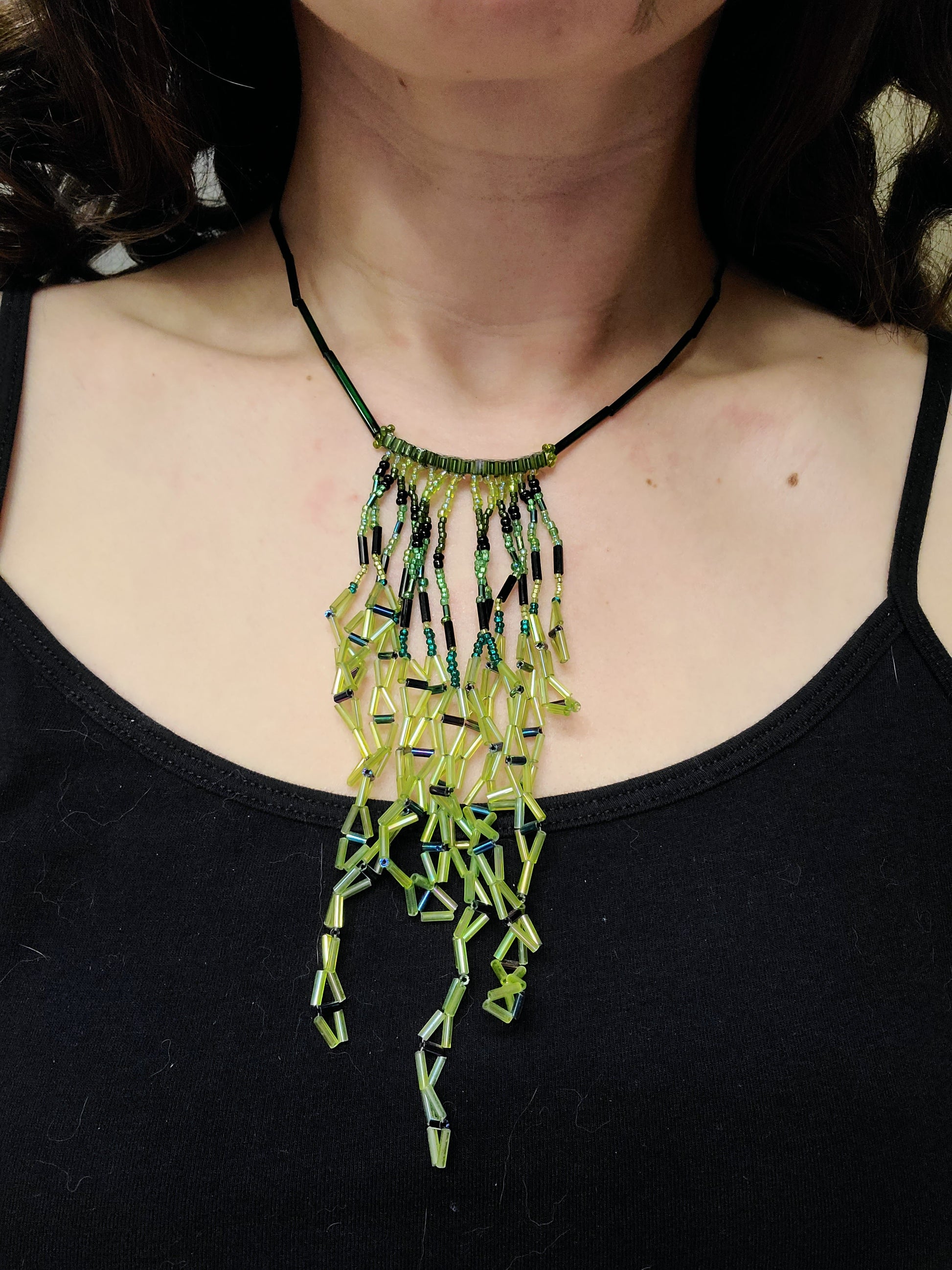 Dark-haired woman wearing lime green diamond-shaped fringe necklace