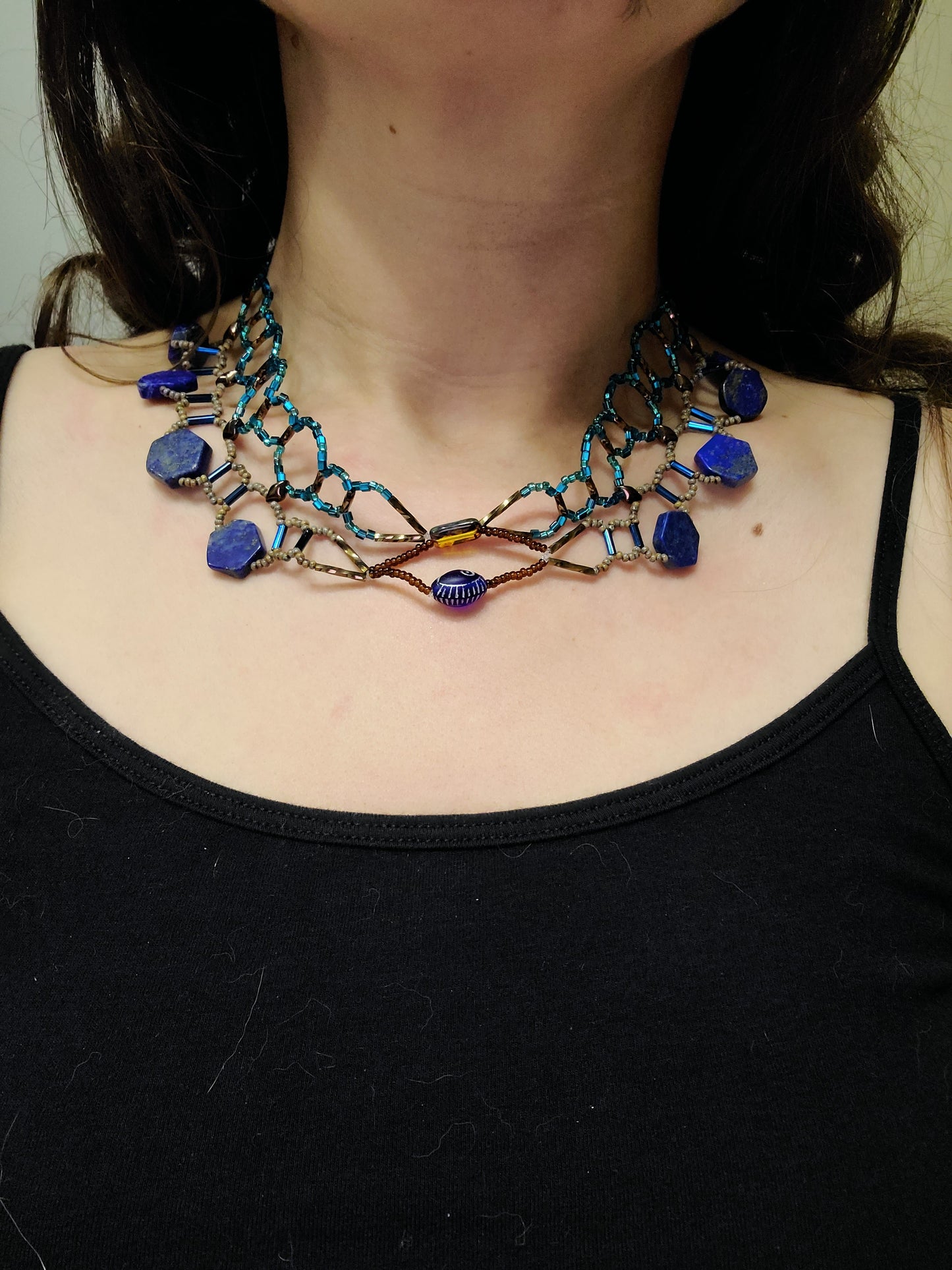 Dark-haired woman wearing lapis collar necklace.