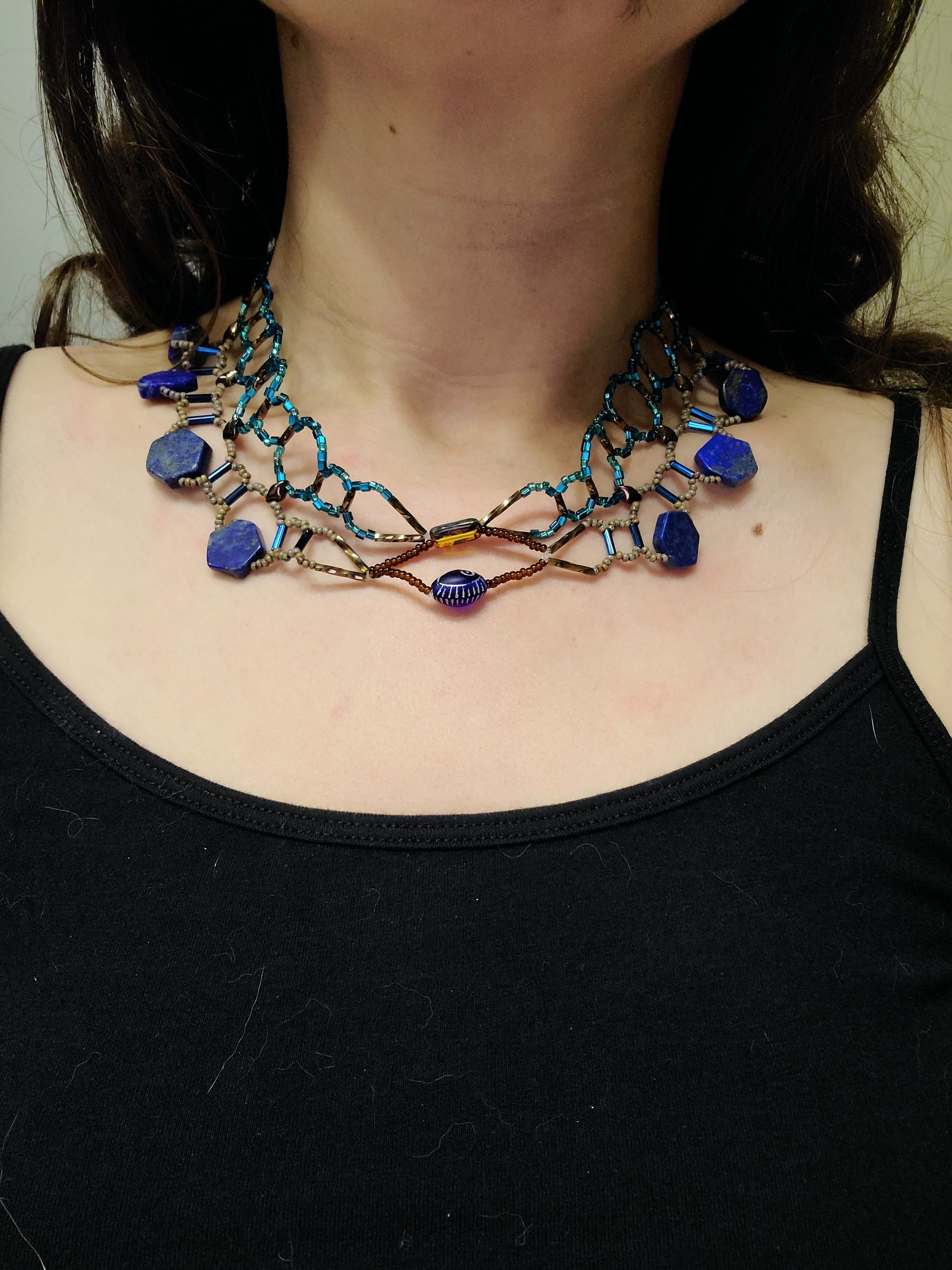 Dark-haired woman wearing lapis collar necklace.