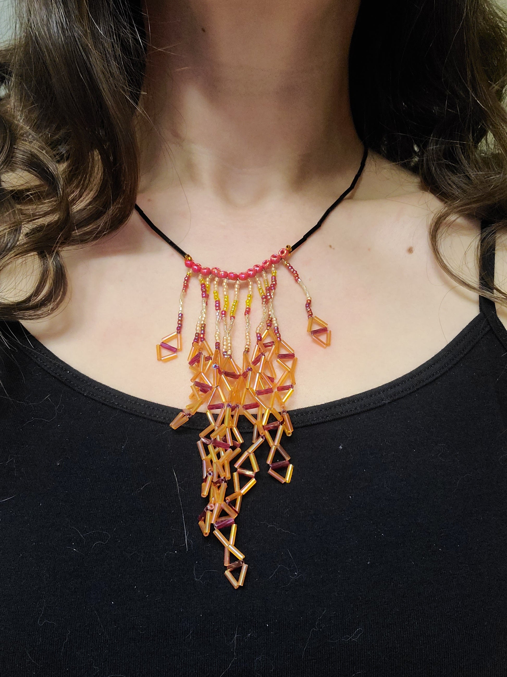 Dark-haired woman wearing orange diamond fringe necklace.