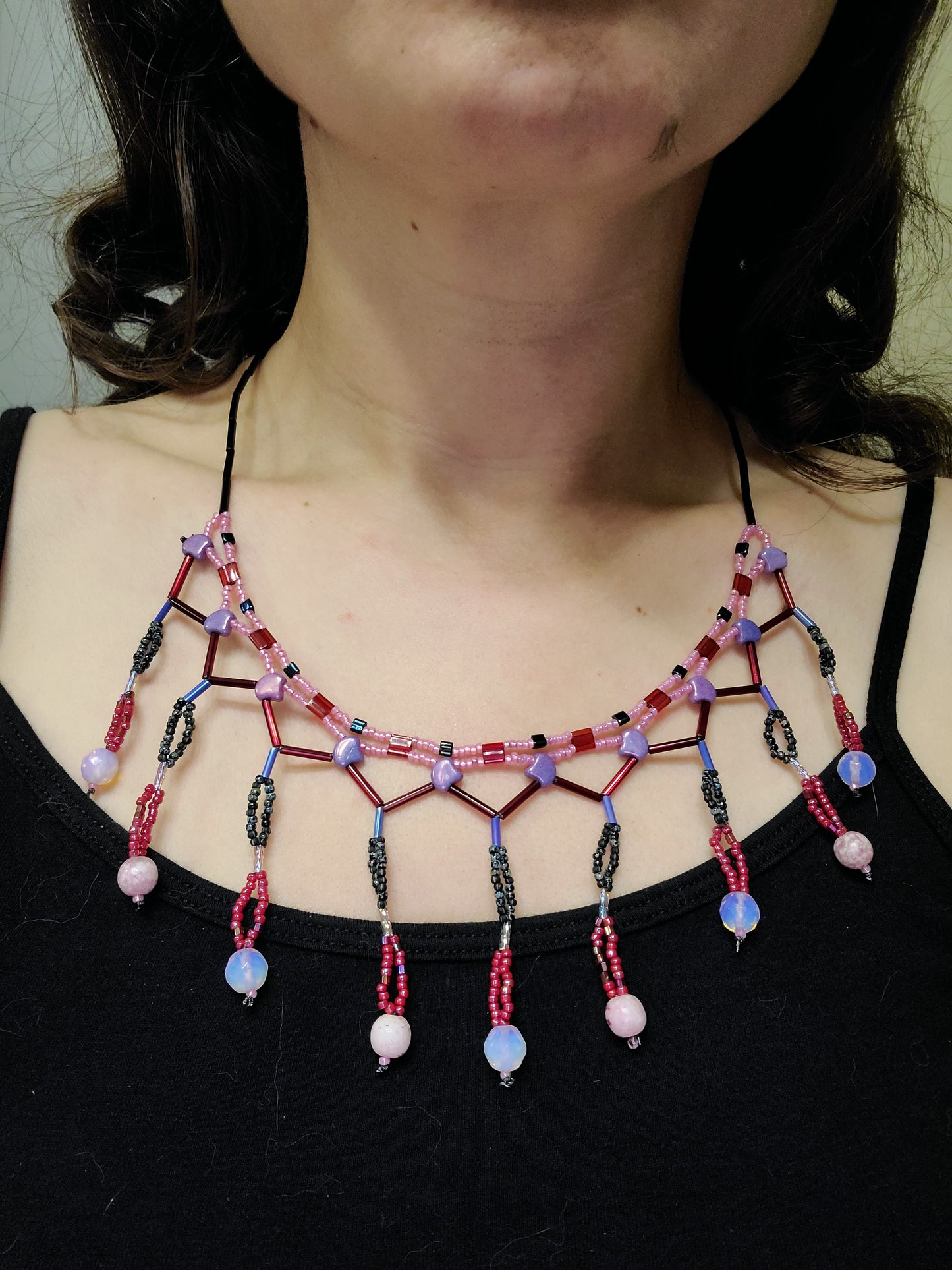 Dark-haired woman wearing red, pink and purple beaded fringe necklace.