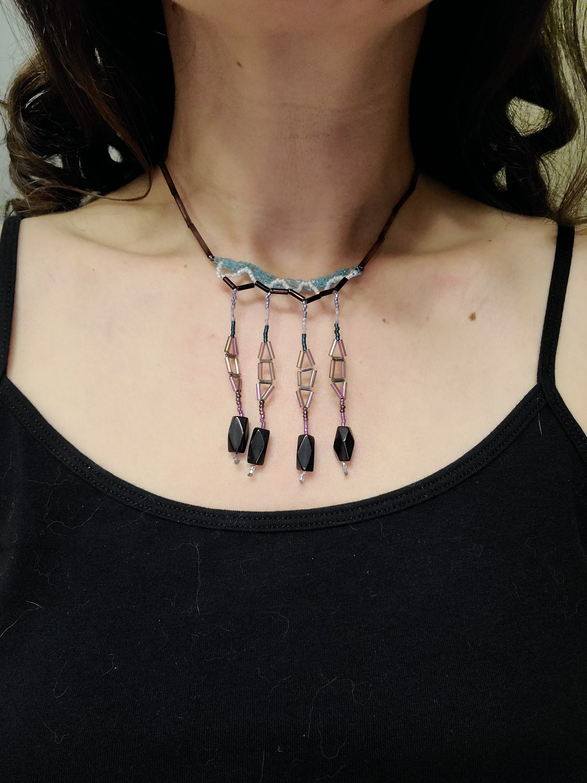 Woman wearing blue and purple chandelier fringe necklace with purple glass beads