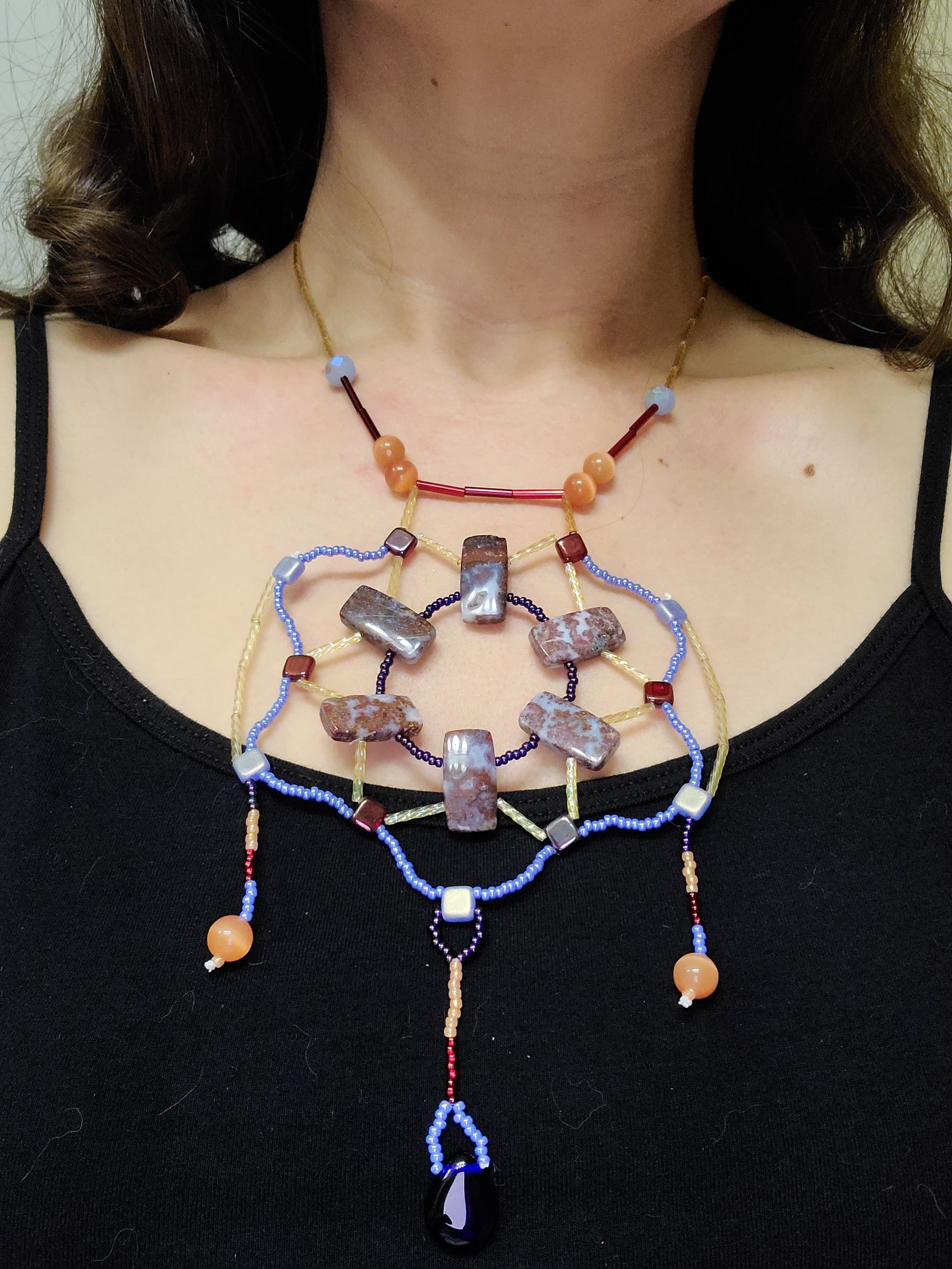 Dark-haired woman wearing maroon, peach and blue Celtic statement necklace