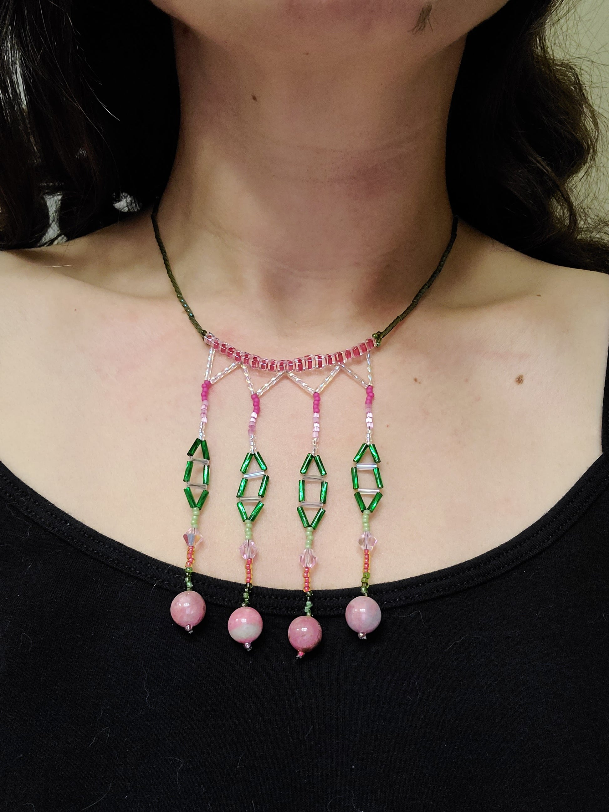 Dark-haired woman wearing green and pink rhodonite beaded necklace