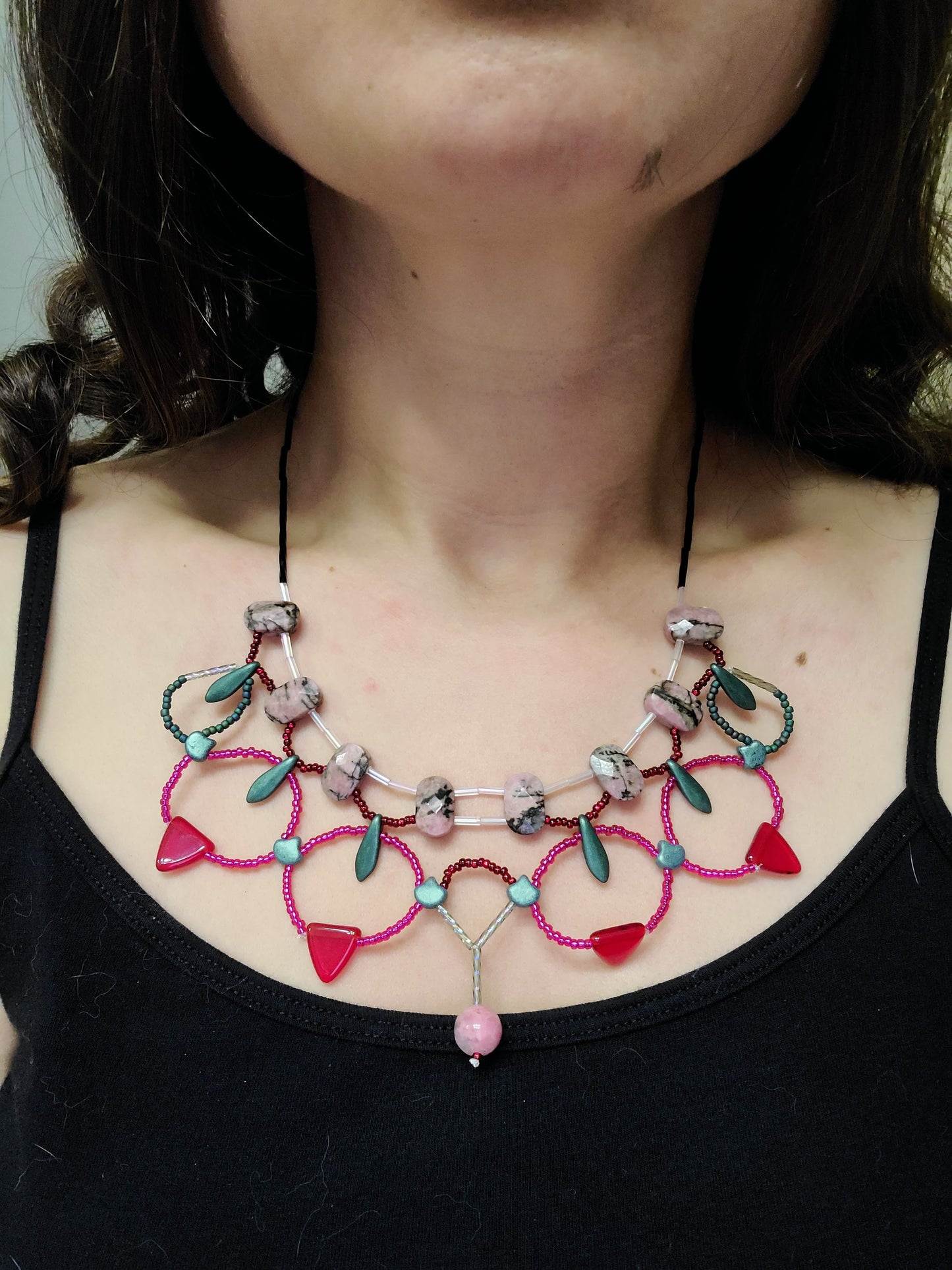 Dark-haired woman wearing rhodonite statement necklace.