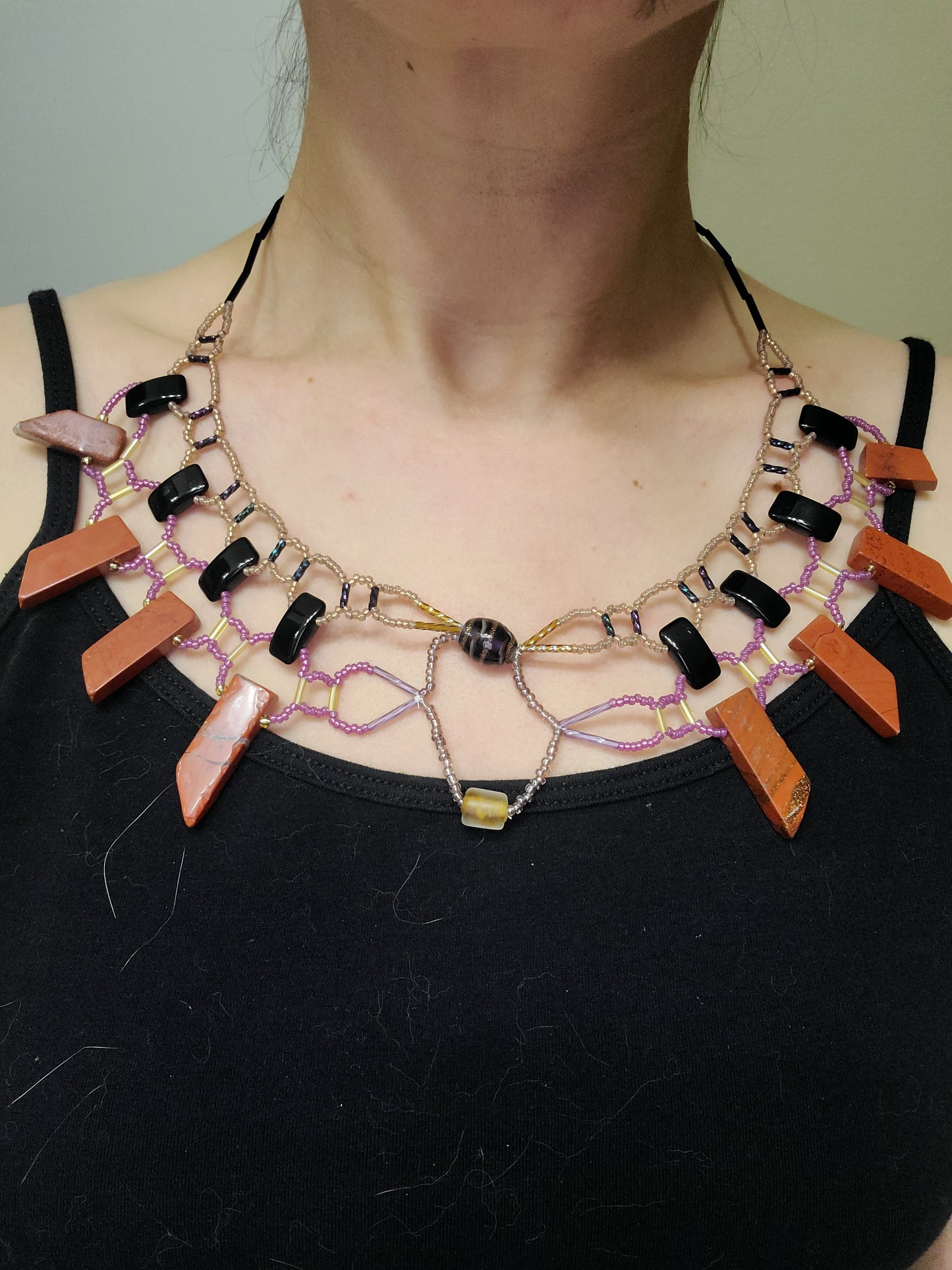 Woman wearing black, pink, and tan collar necklace with jasper beads.
