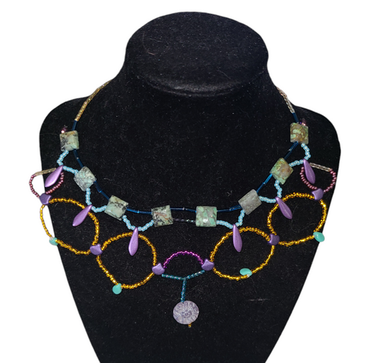 African turquoise necklace on necklace form, featuring purple and teal glass beads. 