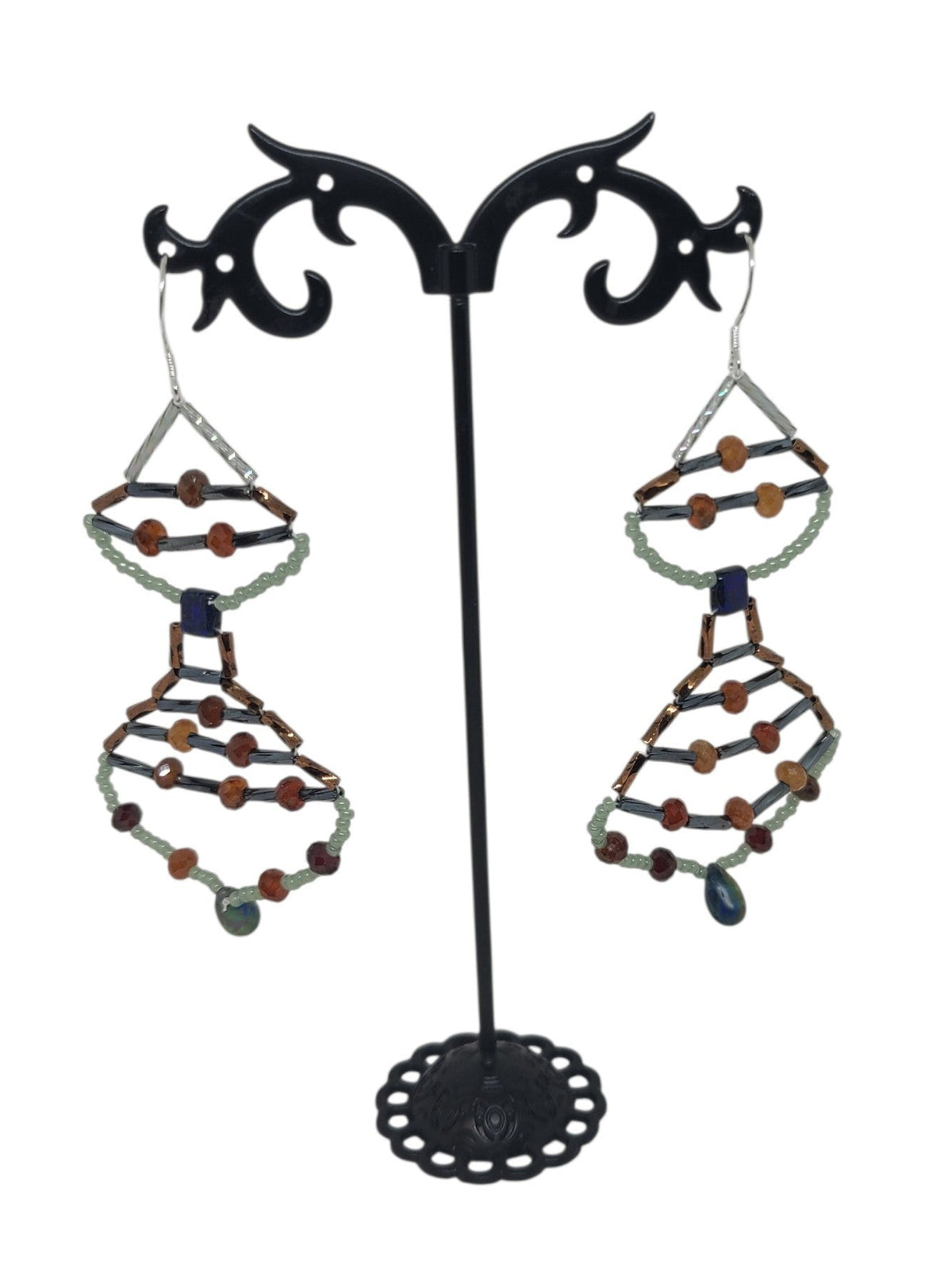 Stacked teardrop drop earrings with hessonite garnet rounds, sage green frame, dark blue glass center bead, and glass teardrop drop.
