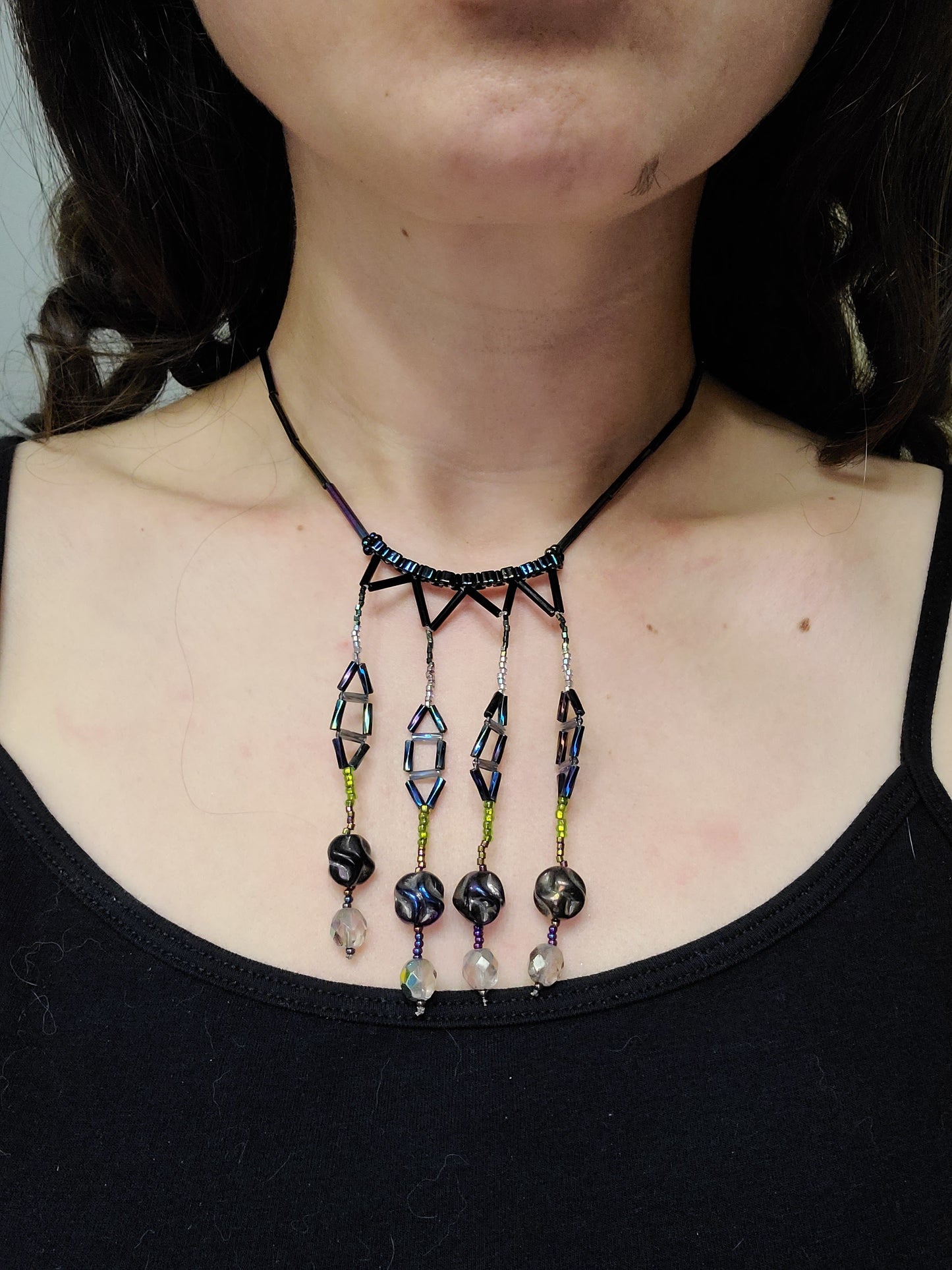 Woman wearing statement necklace with green toned fringe