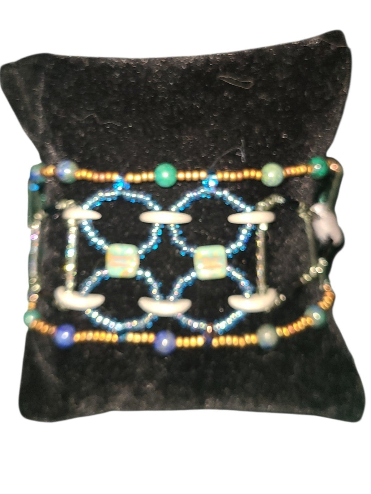 Wide interlaced beaded cuff in sage moss agate, teal chrysocolla, and blue iridescent seed beads on neutral background