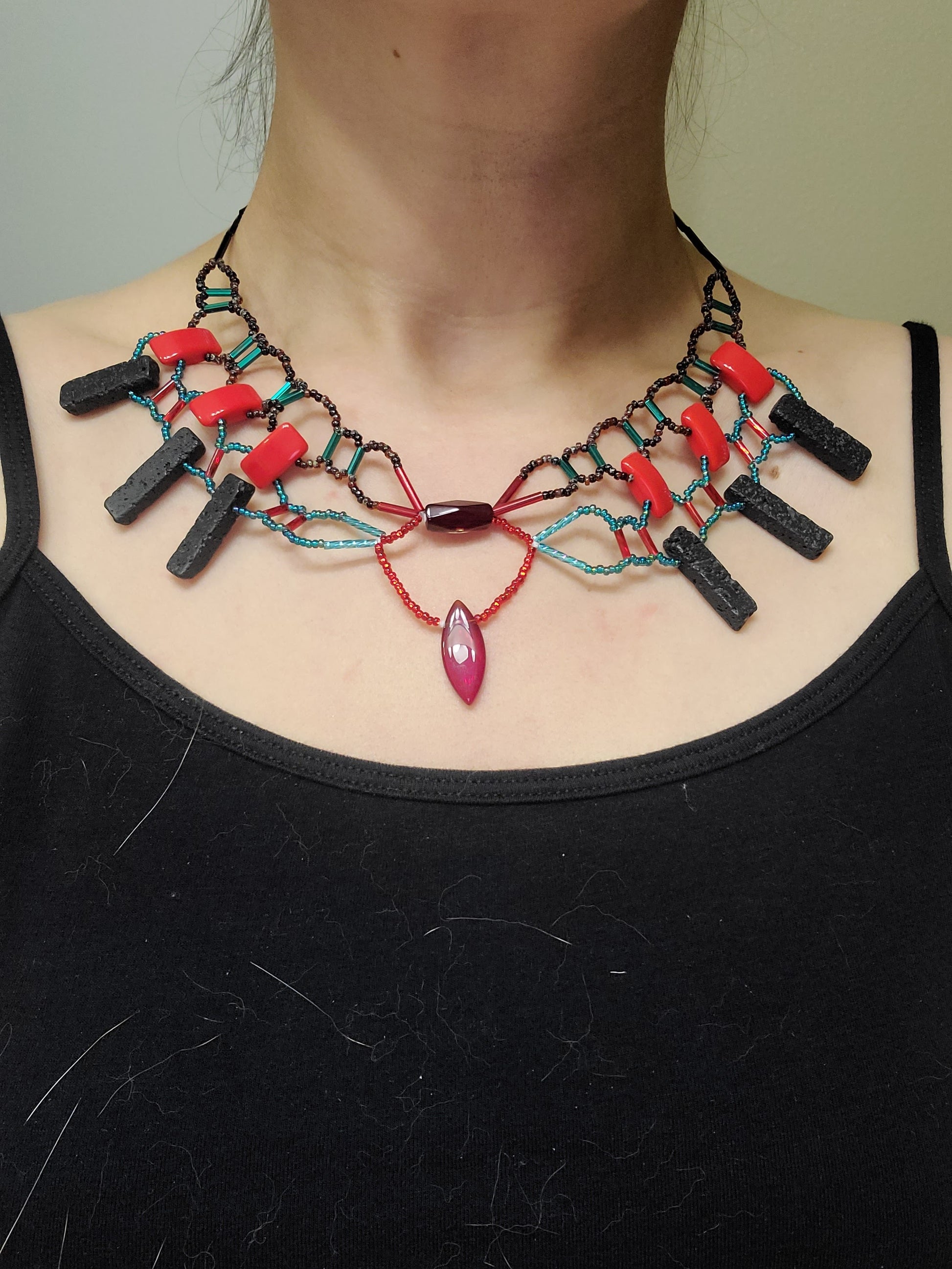 Woman wearing red, teal, and black lava collar necklace