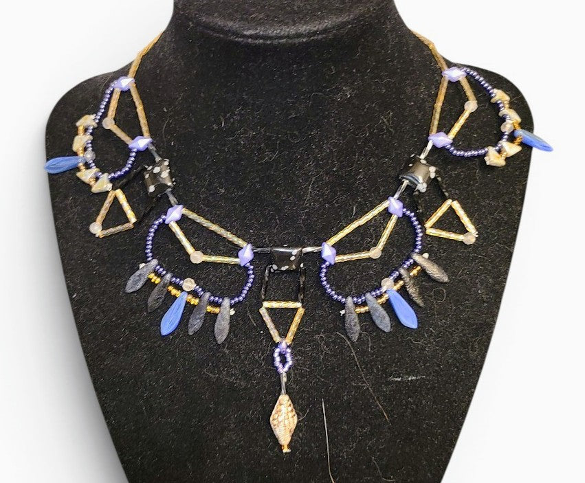 Snowflake obsidian geometric beaded statement necklace with gold brass tube framework and blue dagger drop fringe, front view