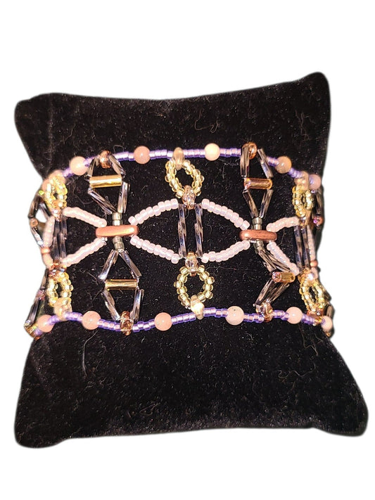 Wide Gothic lattice beaded cuff bracelet in gunmetal, copper, amber, and peach sunstone on a neutral background